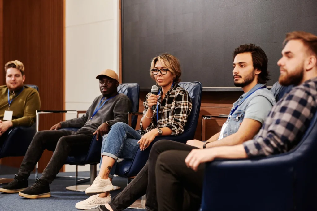 A diverse group of individuals engaged in an informative panel discussion at an indoor event.